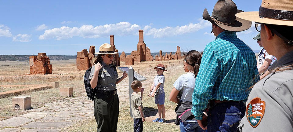 Female ranger speaking to visitors in front of adobe ruins Female ranger speaking to visitors in front of adobe ruins