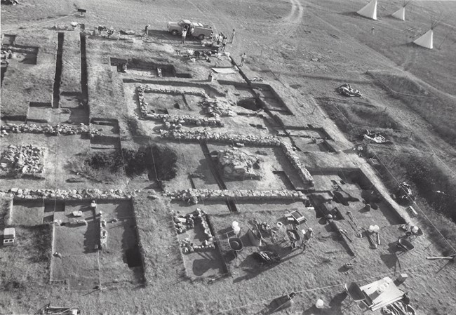 Excavations dug geometrically with very rectangular shapes. There are exposed stone foundations.