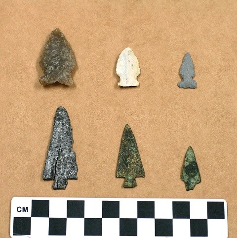 Six sharp tipped triangles made from rough stone and rusty metal. The stone ones are gray and white. The metal ones are discolored to appear green.