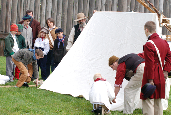Boys in the Young Engage Program learn how to erect a tent in the field.
