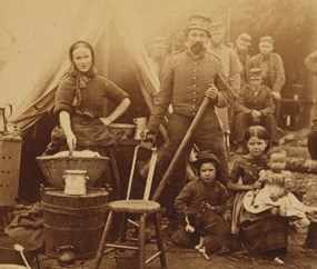 historic image of a Civil War-era washerwoman, man, and two children outside a tent