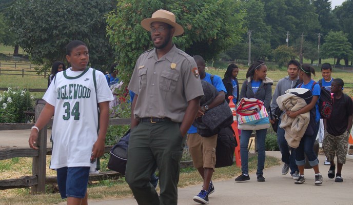 Image of ranger walking on a trail and speaking to students.