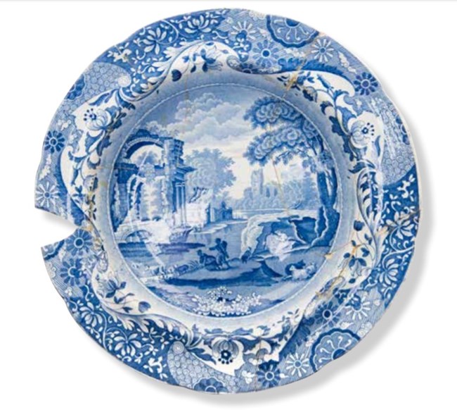 A blue and white ceramic plate that has been glued together.