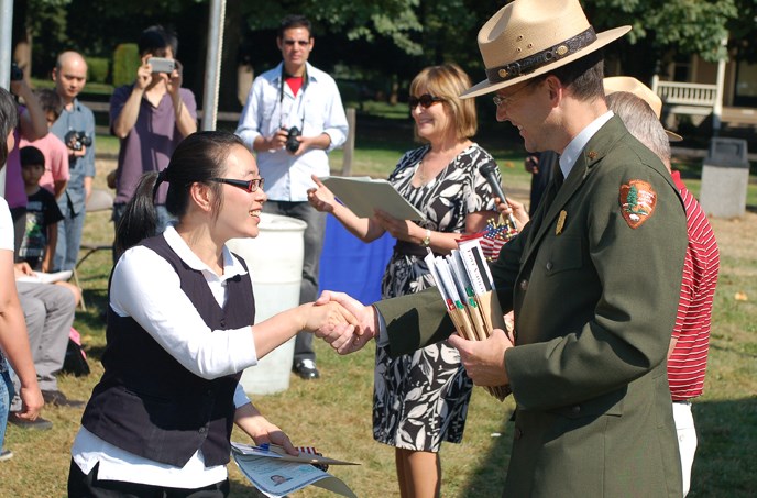 Image of Chief Ranger Shine greeting a new U.S. citizen at the annual Citizenship Ceremony at the Bandstand at Fort Vancouver NHS.
