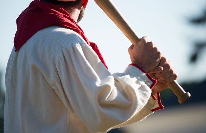 A costumed batter holds a bat awaiting a pitch