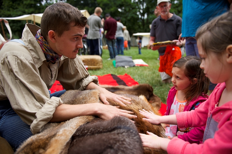 A costumed 1840s re-enactor shares the history of the fur trade with children at the Brigade Encampment