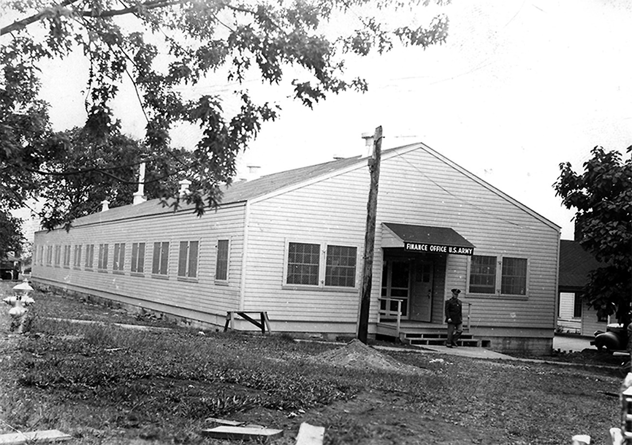 Photo of building with sign reading U.S. Army Finance Office. A man in military uniform is walking out of the building.