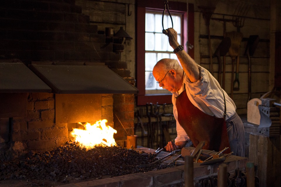 Christmas at FOVA 2018 - Photo by Junelle Lawry Photo of a blacksmith working over a forge.