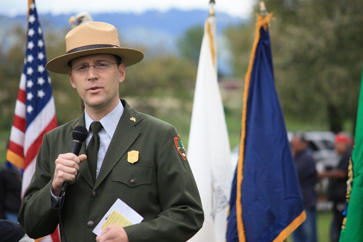 Photo of Greg Shine in park ranger uniform speaking to the crowd at the Nez Perce Chief red Heart Reconciliation Event in 2013