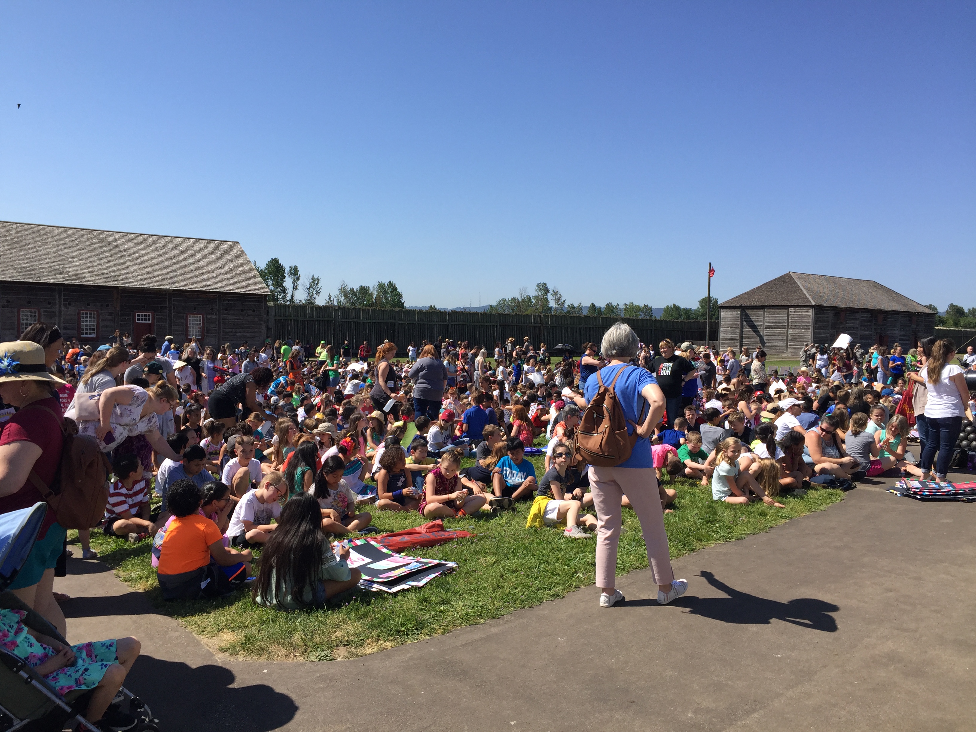 Crowd of children within fort stockade walls, outdoors.