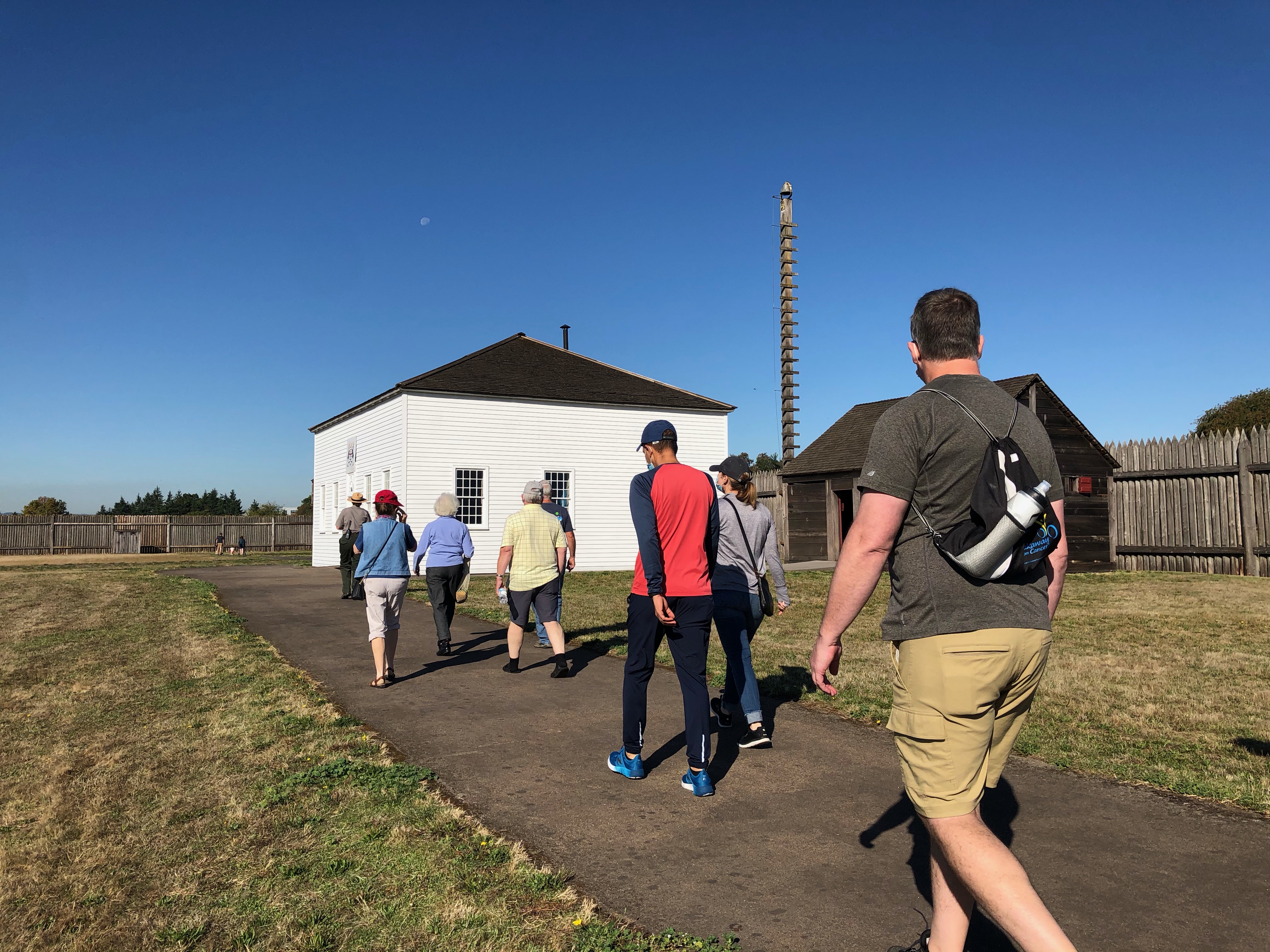 Ranger-led tour People walk towards a white building led by a park ranger inside reconstructed Fort Vancouver