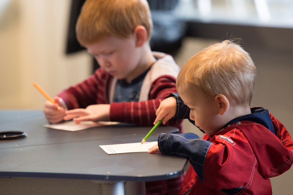 Photo of two young children coloring at a table.