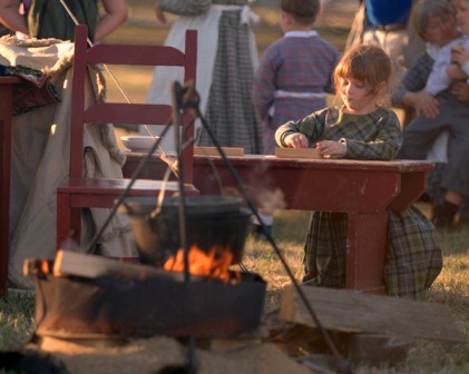 A youth volunteer plays dominoes in the Oregon Trail Camp.