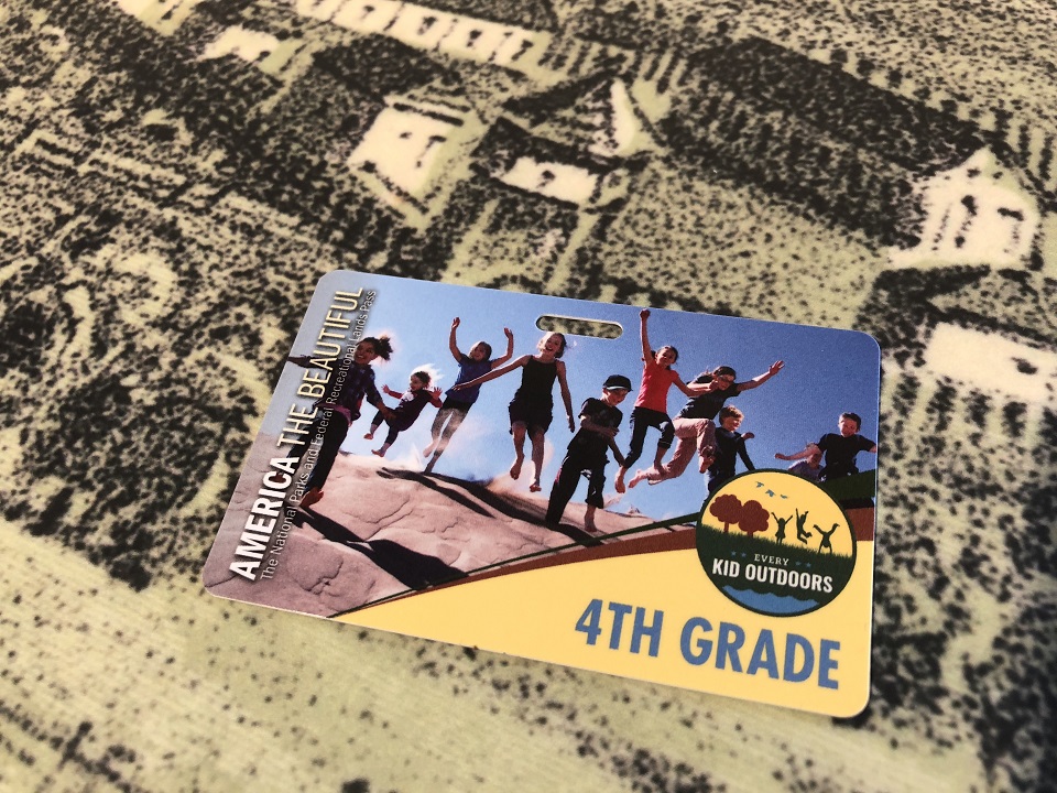 An Every Kid Outdoors pass sits on an an exhibit panel showing an historic image of Fort Vancouver.