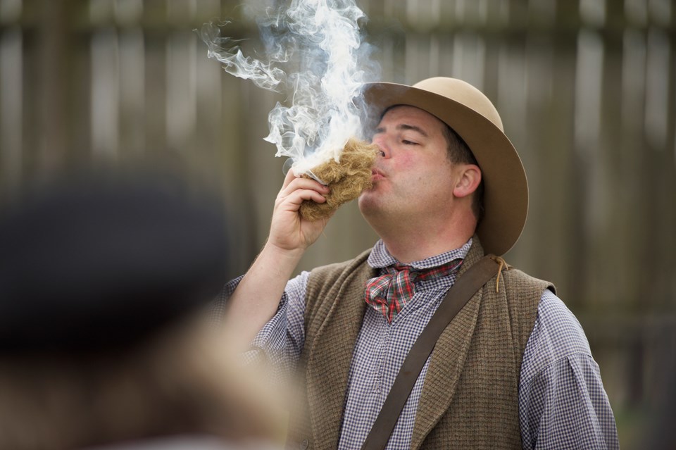 Costumed ranger blows on fire starting material to start flame