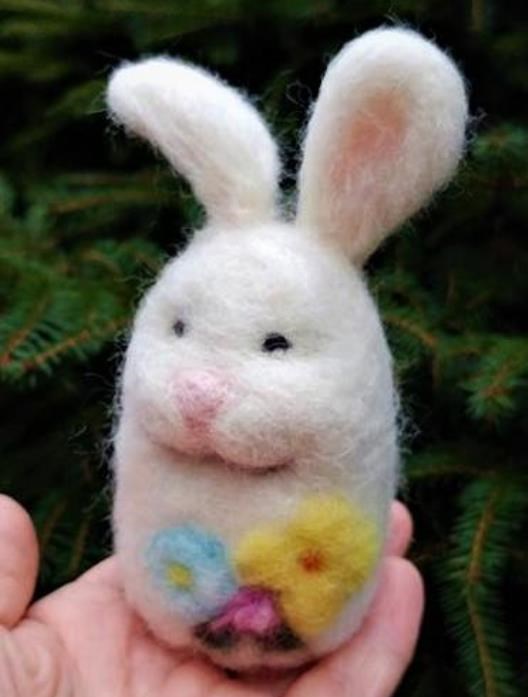Photo of hand holding felted rabbit with colorful felted eggs.