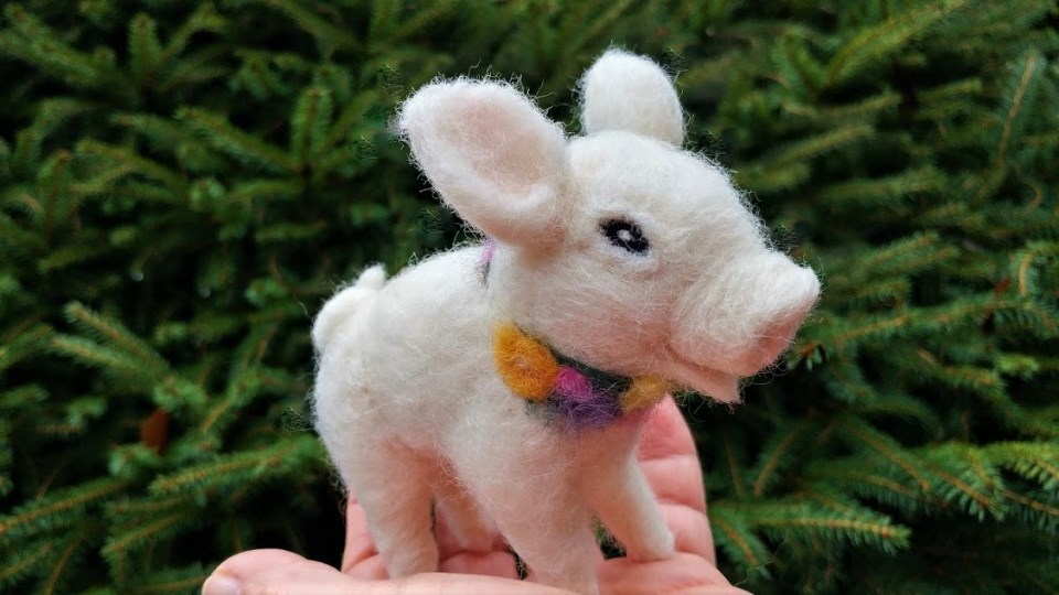 Petal the Piglet Photo of hand holding small felted pig.
