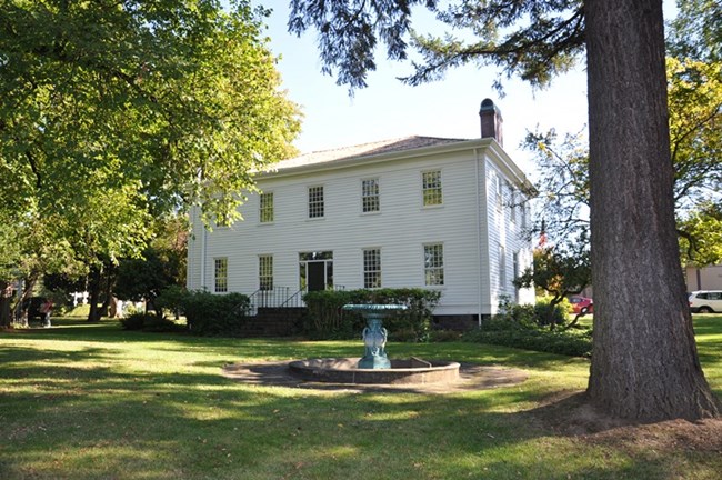 A white house sits in a grassy park.