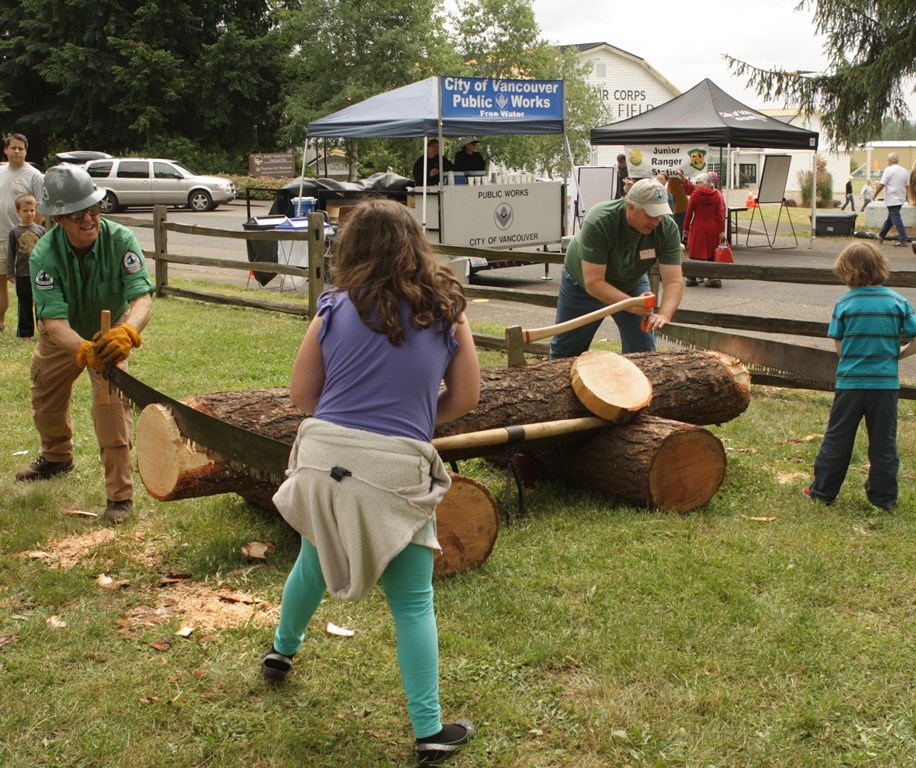 Sawyers and children work together to saw a log at Get Outdoors Day