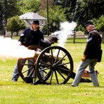 three uniformed soldiers fire the mountain howitzer