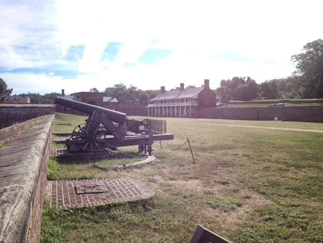 A 24lb cannon on a carriage on the fort wall on a sunny day. A 24lb cannon on a carriage on the fort wall on a sunny day.