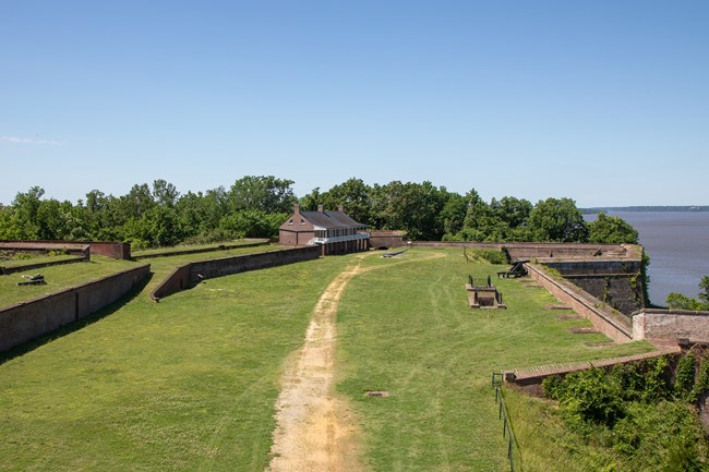 A large grassy area encircled by brick walls and buildings.