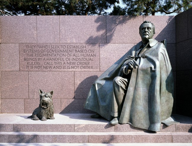 Larger-than-life bronze statue of man covered in a long cape next to a a Scottish Terrier dog.