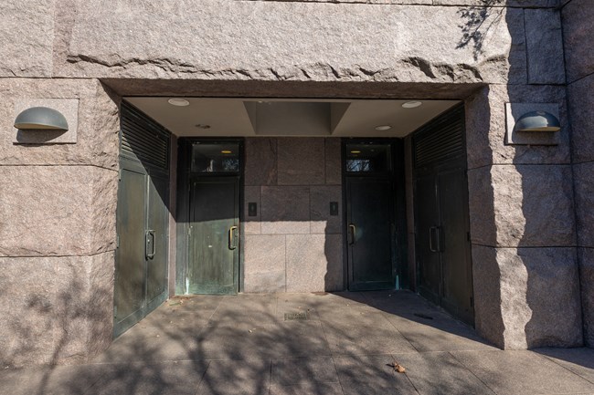 Two large doors sit in an aclove, indicating women's and men's. Braille is available under each restroom sign to indicate gender. Each door has a handle.