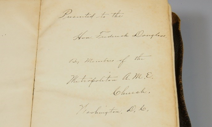 The cursive, handwritten, ink inscription inside the Bible reads "Presented to the Hon. Frederick Douglass by members of the Metropolitan A.M.E. Church, Washington, D.C."