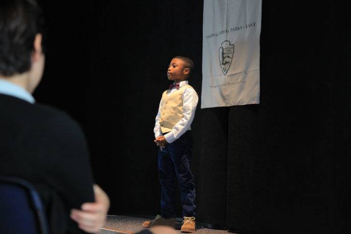 A student gives a speech from a stage
