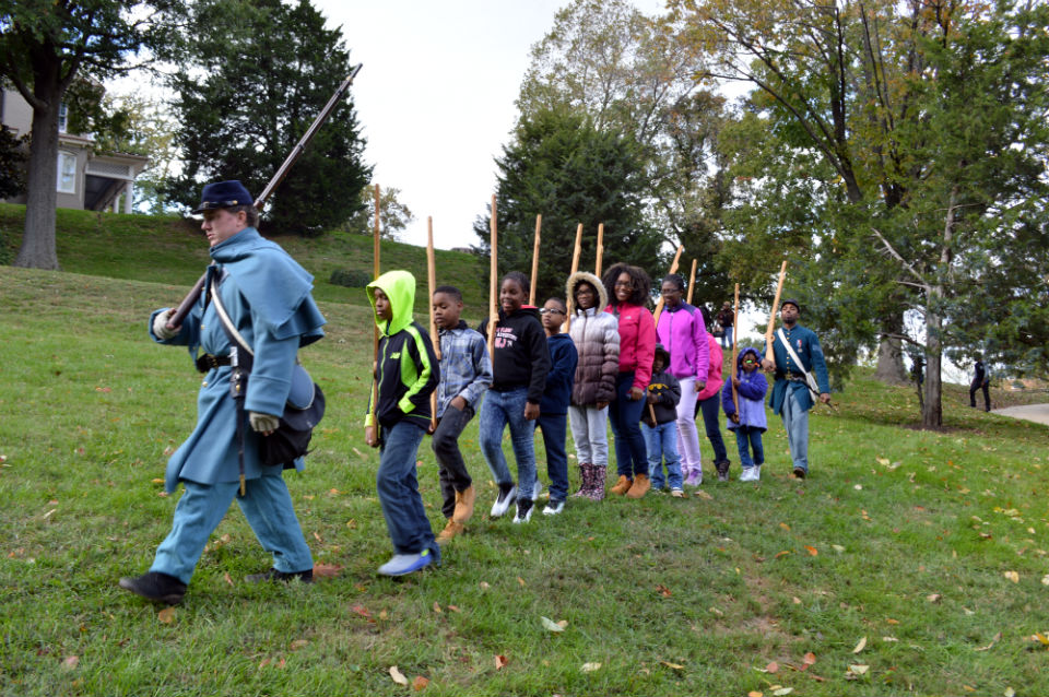 A line of children with wooden rifles follow a man dressed in a Civil War uniform A line of children with wooden rifles follow a man dressed in a Civil War uniform