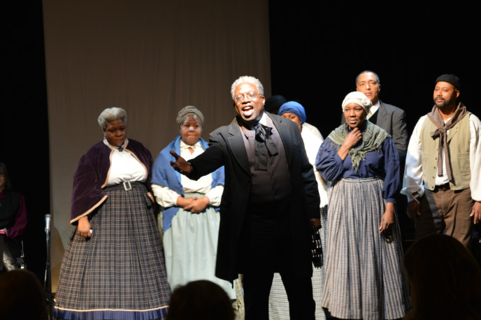 A man in historical clothing sings with a group of backup singers A man in historical clothing sings with a group of backup singers