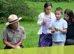 A ranger listening to Good Neighbors students reading in the landscape