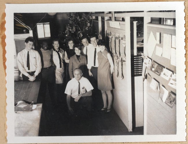 Black and white of people gathered around, holding each other and posing for picture.