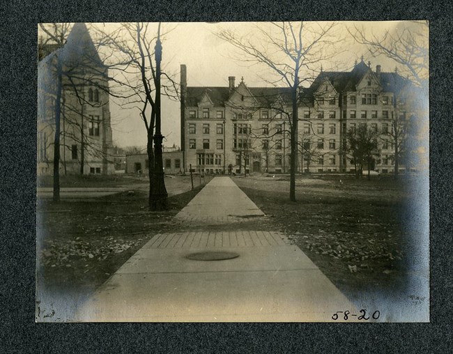 black and white image of pathway headed towards large building