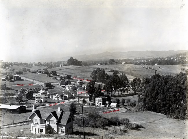 Aerial view of community with homes grouped together and open green space in distance