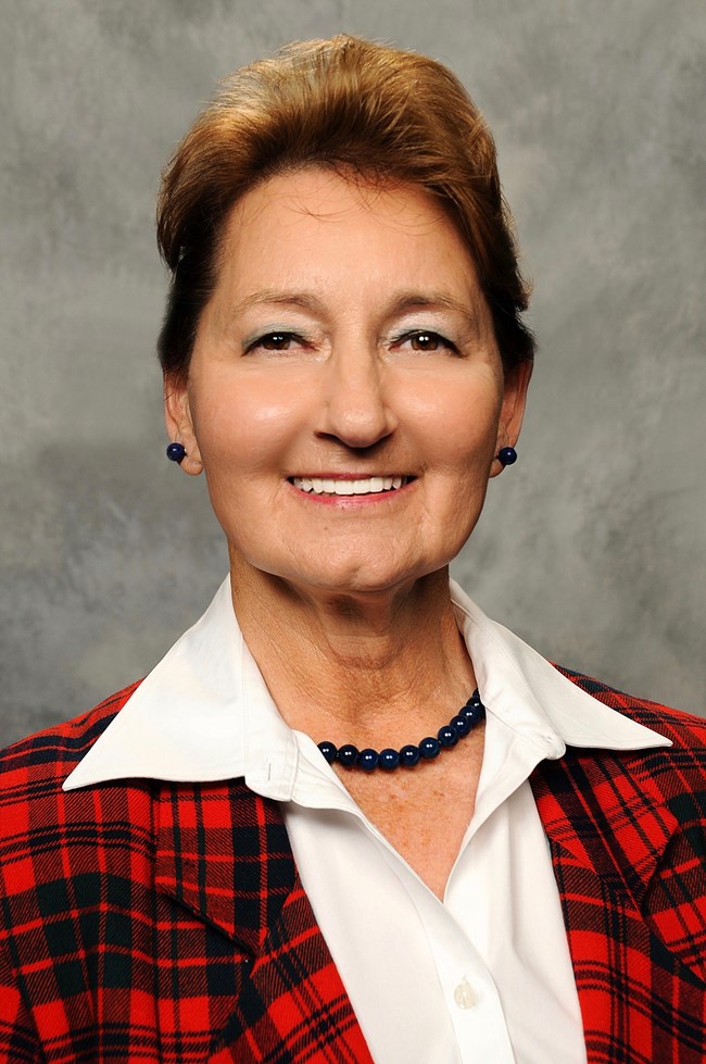 woman smiles wearing red plaid jacket.