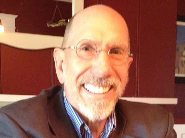 man smiling at camera wearing glasses.