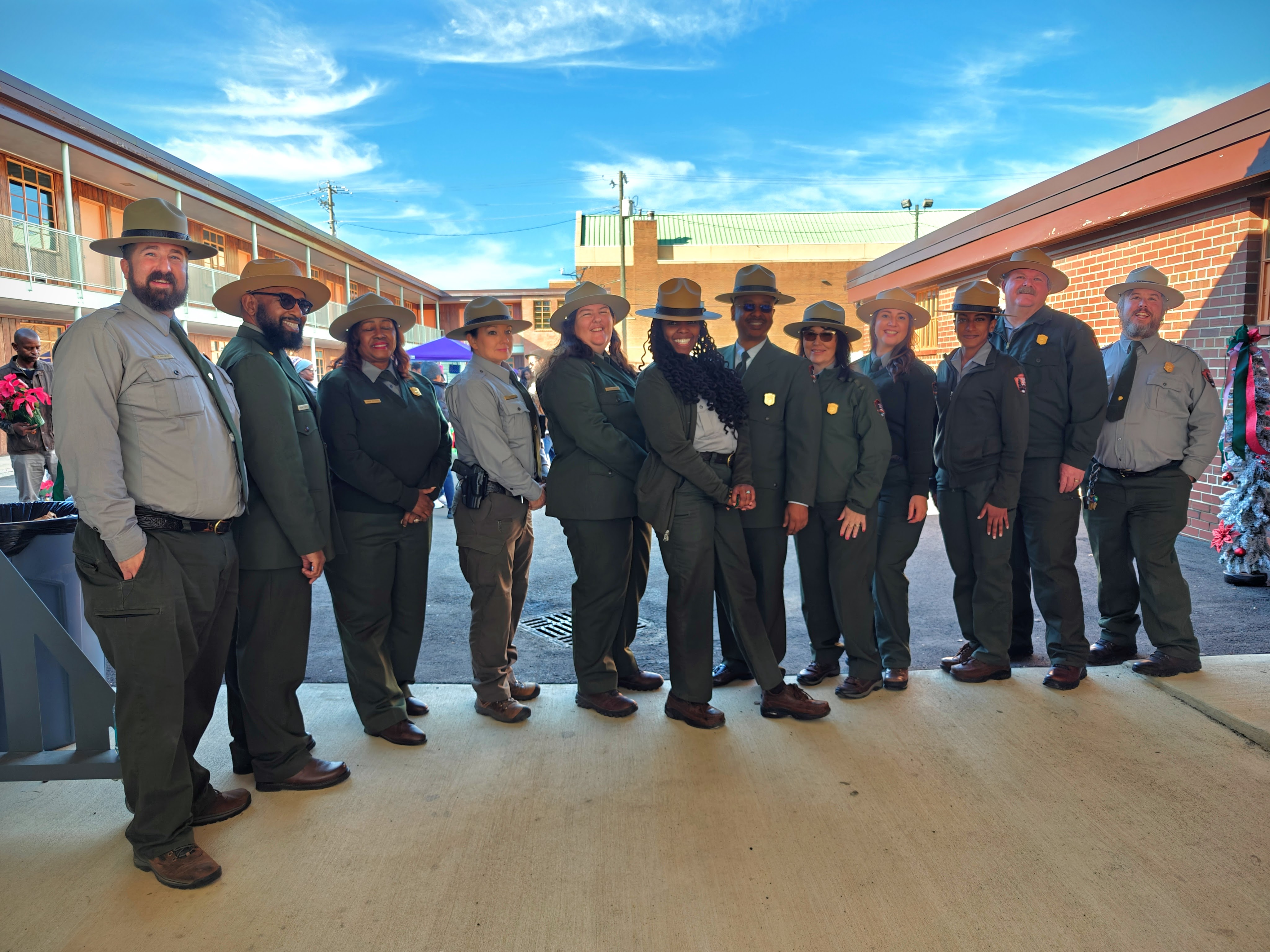 A group of rangers stand in front of a historic two story hotel.