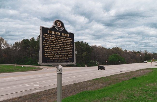 A metal sign describing the Freedom Riders overlooks a section of Highway 202.