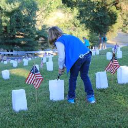 A girl scout lights a luminary candle in the Fredericksburg National Cemetery with American flags on the graves A girl scout lights a luminary candle in the Fredericksburg National Cemetery with American flags on the graves