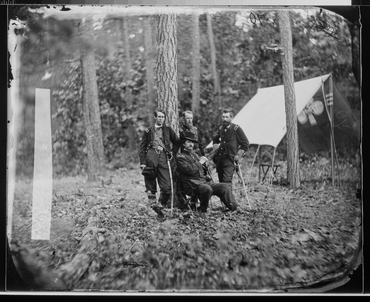 Gen. Winfield S. Hancock and Generals Francis C. Barlow, David B. Birney, John Gibbon Black and white photograph of military general sitting with three men standing behind him.