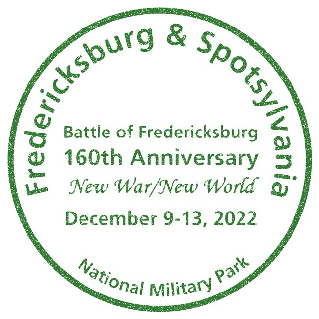 A green circular park stamp with the park name around the edges, Fredericksburg and Spotsylvania National Military Park, and in the center, Battle of Fredericksburg, 160th Anniversary, New War/New World, December 9-13