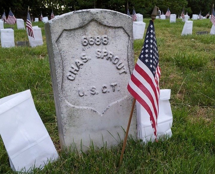 Grave of Charles Sprout in National Cemetery with American flag and two luminaries flanking stone Grave of Charles Sprout in National Cemetery with American flag and two luminaries flanking stone