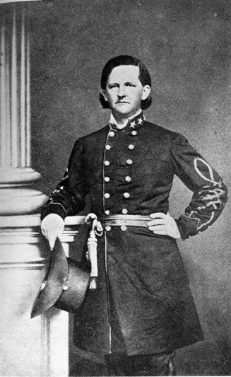 Full image of Thomas Cobb dressed in military uniform holding hat and leaning against a pillar
