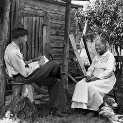 Ralph Happel (seated) inteviews Phenie Tapp (seated with dog at feet) in front of farm house Ralph Happel (seated) inteviews Phenie Tapp (seated with dog at feet) in front of farm house