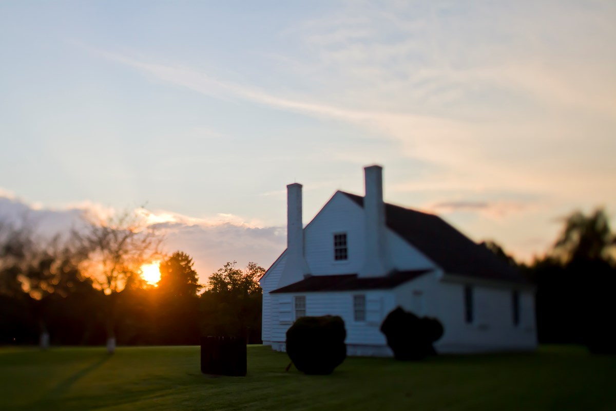 A small white farm house at sunset.