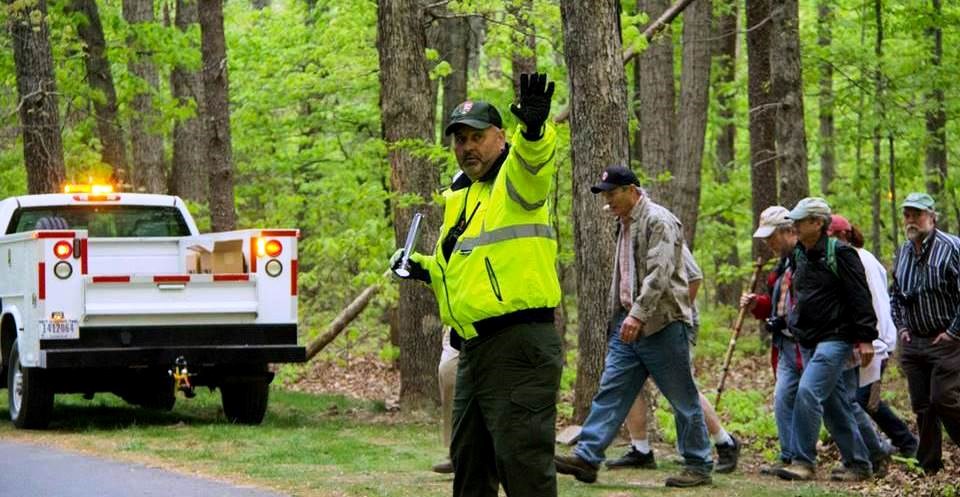 Maintenance employee stops traffic as visitors cross park road