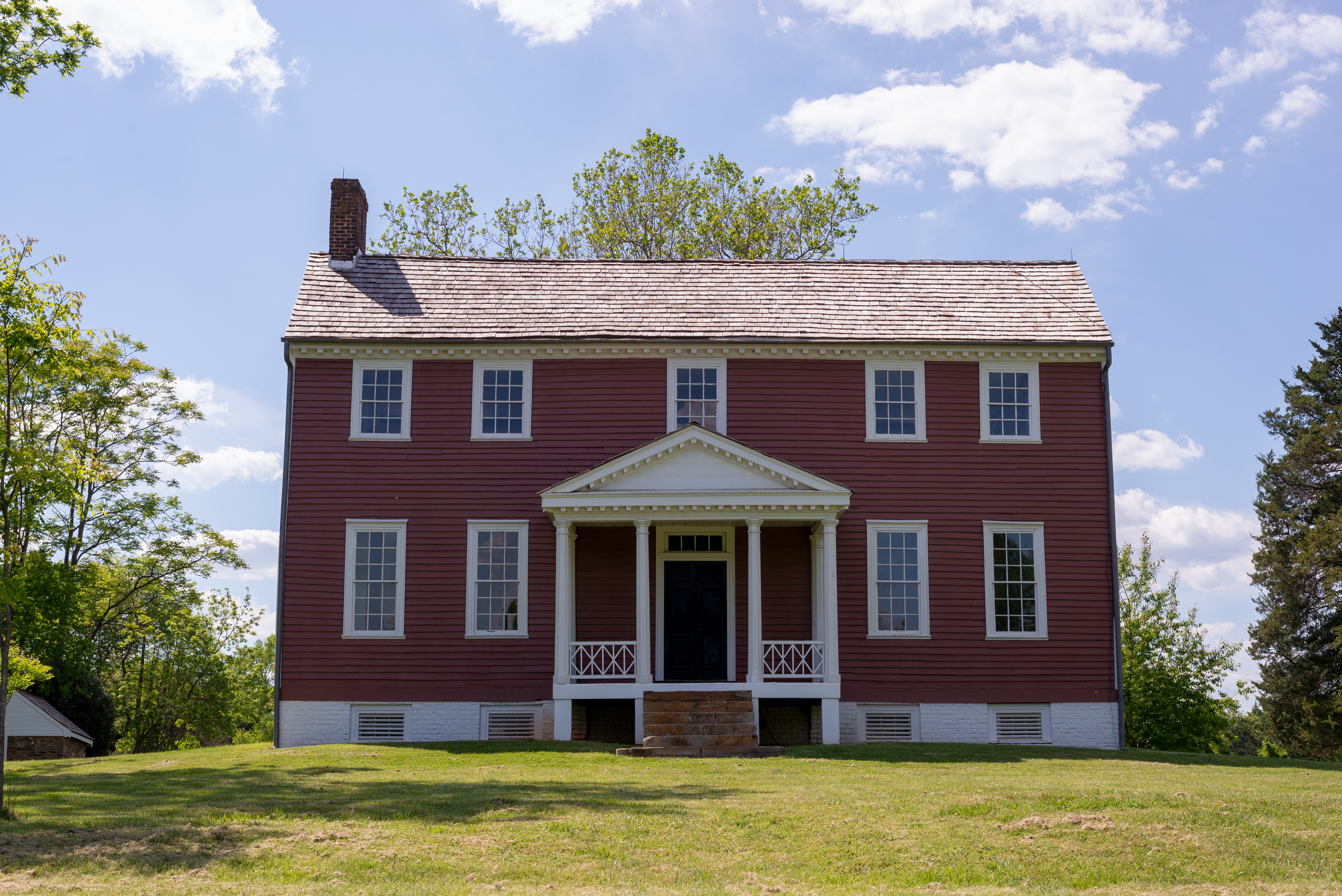 A two story red farm house with columned porch.