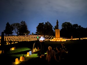 Ranger speaking in a cemetery lit by luminarias